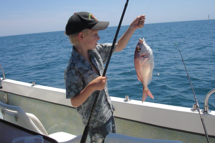 a person holding a fish on a boat in a body of water