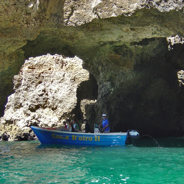 a small boat in a body of water under caves
